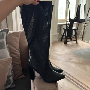 Boots / Stövlar / Med klack   - Snygga svarta stövlar med spetsig tå. De har en hög klack och når upp till knäna, vilket ger en elegant look. Perfekta för att lyfta vilken outfit som helst. Använda några få gånger, pris kan diskuteras vid snabb affär 