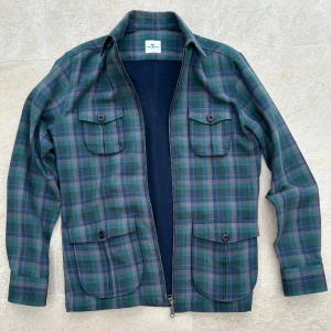 Rutig overshirt från john henric - Snygg rutig overshirt i grönt och blått från john henric. Jackan har en dragkedja framtill och två praktiska bröstfickor med knappar. Perfekt för lager-på-lager-stil under höst och vår. Passar bra till mig som är 182 men funkar även till någon som är några cm längre. Har du några frågor så är det bara att skriva!