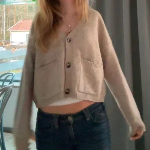Beige kofta med knappar - Säljer en mysig beige kofta med stora knappar framtill. Koftan har långa ärmar och två fickor på framsidan. Perfekt för kyligare dagar. Köpt ny för 699