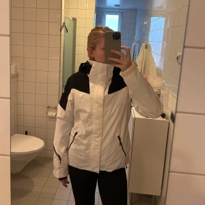 Skidjacka vit och svart - Superfin skidjacka från McKinley. Vit med svarta detaljer. Jackan är använd 3 säsonger och är därför i mycket bra skick. Den har innerficka vid bröstet, fickor på sidorna och en ficka till liftkortet på ärmen. Jackan har även snölås vid midjan. 