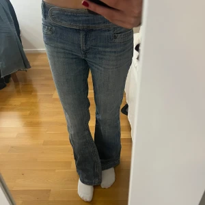 Low waist vintage bootcut jeans - Snygga blå jeans med bootcut-stil och låg midja. Perfekta för en avslappnad look. Klassisk femficksdesign och knappgylf.