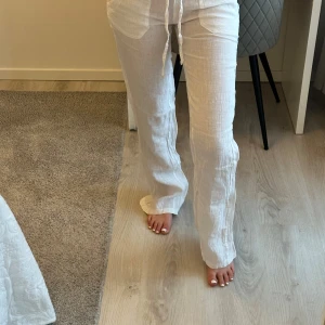 Vita linnebyxor från Chelsea Girls - Snygga vita linnebyxor från Chelsea Girls med en avslappnad passform. Byxorna har en bekväm dragsko i midjan och raka ben. Perfekta för en somrig look. Aldrig använt storlek xs