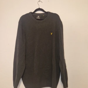 2 tröjor från Lyle & Scott - Säljer en stilren grå tröja från Lyle & Scott med deras ikoniska gula logga på bröstet. Tröjan har en klassisk rund hals och långa ärmar, perfekt för en avslappnad look. Passar bra till både jeans och chinos.