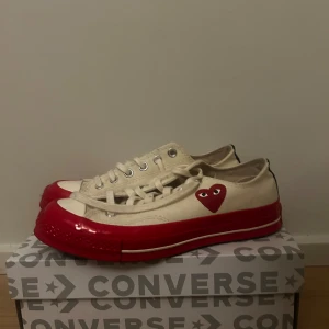 Converse x Comme des Garçons sneakers - Snygga Converse sneakers i samarbete med Comme des Garçons. Skorna är vita med en röd sula och har det ikoniska hjärtmotivet på sidan. Perfekta för dig som vill ha en unik och stilren look.❤️❤️