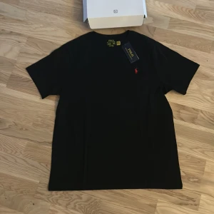Svart t-shirt från Ralph Lauren - Säljer en stilren svart t-shirt från Ralph lauren. Den är helt ny och oanvänd och köpt från NK. Nypris 700kr, skick 10/10. Storlek 170 vilket motsvarar XS-S i vuxenstorlek.