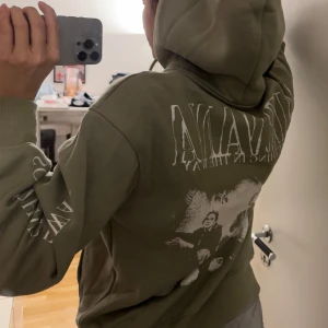 Olivgrön hoodie med Nirvana-tryck - Säljer en olivgrön hoodie med tryck av bandet Nirvana. Hoodien har en klassisk design med en stor ficka framtill och justerbar huva. Perfekt för dig som älskar rock och vill ha en bekväm och stilren tröja.