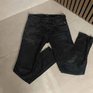 Svarta jeans från Replay - Snygga svarta jeans från Replay i modellen Anbass. De har en klassisk femficksdesign med dragkedja och knapp. Perfekta för en stilren look.