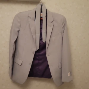 Ljusgrå kostym från  - Snygg ljusgrå kostym från  Opposuits med kavaj och byxor. Kavajen har två knappar och klassiska fickor. Byxorna är raka och stilrena slips