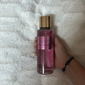 Victoria's Secret Pure Seduction Body Mist - Säljer en Victoria's Secret Pure Seduction body mist. Flaskan är genomskinlig med en rosa vätska inuti och har en guldfärgad kork. Den har en fräsch och söt doft av juiced plum och crushed freesia. Perfekt för att fräscha upp sig under dagen eller för en kväll ute. Flaskan rymmer 250 ml och har aldrig använts❤️