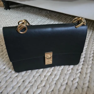 Svart väska  - Superfin svart väska med guldiga detaljer! Använd ett antal gånger men förtfarande i nytt/ bra skick. Köptes via Zalando. Pris kan förhandlas! 
