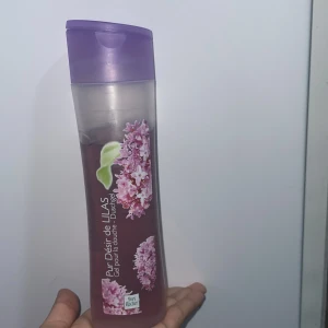 Pur Désir de Lilas Duschgel - Säljer en härlig duschgel från Yves Rocher med doft av syrén. Flaskan är genomskinlig med lila detaljer och ett vackert blommönster. Den innehåller 200 ml och har en praktisk flip-top-kork. Perfekt för en fräsch och blommig duschupplevelse! orginal pris: ca 315kr