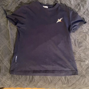Axel Arigato - T-Shirt - En fin t-shirt från Axel Arigato i marinblå färg. Sparsamt använd. 
