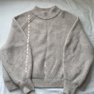 Beige stickad tröja från H&M - säljer en varm och mysig beige stickad tröja från H&M. den har en hög krage och är perfekt för höst och vinter.