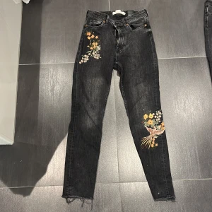 Jeans med blommor från hm  - Grå svarta med orange,rosa och gula blommor 
