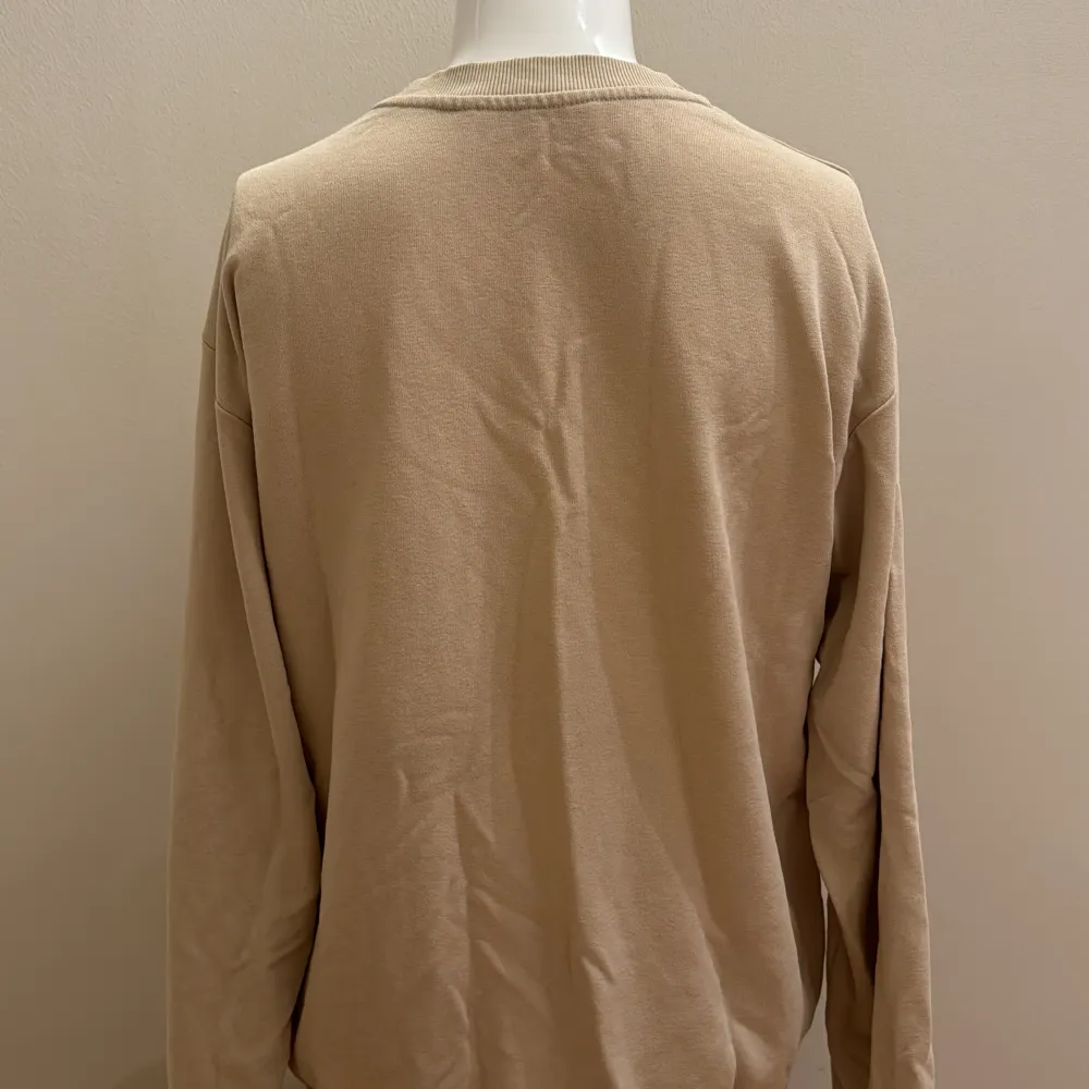 En tunn, beige sweatshirt med tryck på framsidan. Bra skick . Neuletakit & Villapaidat.