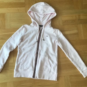 Ljusrosa huvtröja från Tommy Hilfiger - Säljer en superfin ljusrosa huvtröja från Tommy Hilfiger. Den har en dragkedja framtill och en liten logga på bröstet. Tröjan är i bra skick och perfekt för vår och höst. Den har en skön passform och är gjord av mjukt bomullsmaterial. Skriv gärna om ni har frågor 💕