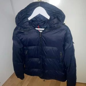 Mörk blå moncler jacka fejk bra sick dm för mer bilder stolek S ✅ - Snygg svart dunjacka från Moncler med huva och dragkedja. Jackan har långa ärmar och praktiska fickor med knappar. Perfekt för kyliga dagar.