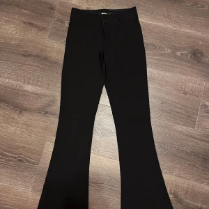 Svarta bootcut byxor från Ginatricot - Snygga svarta bootcut byxor från Ginatricot med låg midja och knappar. 