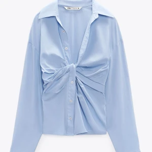 Ljusblå skjorta från Zara - Snygg ljusblå skjorta  från Zara med knytning framtill och klassisk krage. Blusen är figursydd med dragkedja. Perfekt för en stilren look.