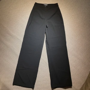 Svarta kostymbyxor - Svarta kostymbyxor från Bershka med hög midja. Byxorna är raka. Mycket bra skick.