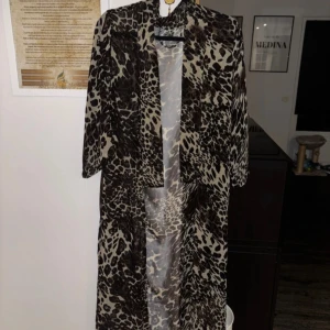 Leopardmönstrad kimono  - Snygg och trendig leopardmönstrad kimono med trekvartsärm. Perfekt för en djärv look. Klänningen har en luftig passform och är tillverkad i ett lätt material.