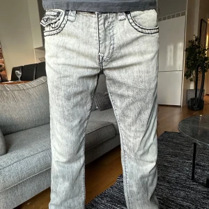 Grå jeans från True Religion - Säljer ett par grå jeans från True Religion med unika bakfickor och kontrastsömmar. Ett par stilrena byxor som passar både till vardags och festligare tillfällen! Hör av dig för fler bilder och specifika mått 💫
