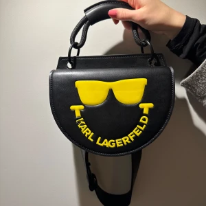 Svart axelväska från Karl Lagerfeld - Helt ny väska från Karl Lagerfeldt. En exklusiv modell som är gjort i samband med samarbetet med Smiley. NYPRIS - 2700kr (helt oanvänd!)