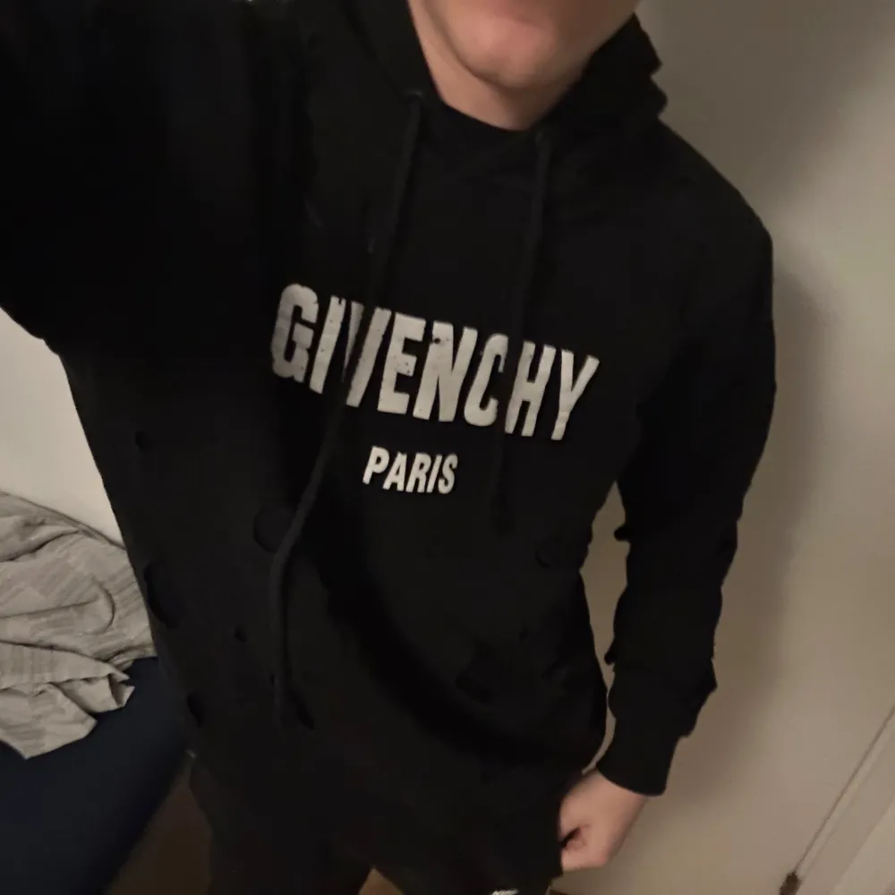 Säljer en stilren svart hoodie från Givenchy med vit logotyp på bröstet. Tröjan har en klassisk design med huva och dragsko. Perfekt för en avslappnad look. Hoodien är äkta köpt i dubai. Nypris är runt 6-10 tusen kr. Hoodien är i ny skick använd ett par gånger bara.. Neuletakit & Villapaidat.