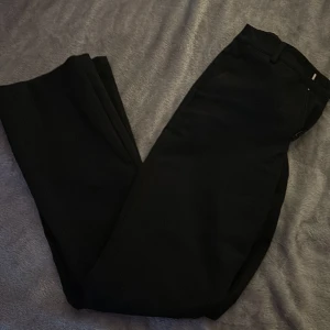 Svarta byxor från Bik Bok - Snygga svarta byxor från Bik Bok i storlek 34. Perfekta för en stilren look med en klassisk passform. Byxorna har en enkel design som gör dem lätta att matcha med olika toppar.