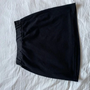 Svart kjol - Snygg svart kortkjol med elastisk midja. Perfekt för en stilren look.