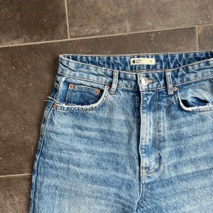 Blå jeans från Gina Tricot - Medium washed blå jeans från Gina Tricot i storlek 36. Highwaist med wide leg. Längd 112 cm, innerbenslängd 82 cm & midja 38 cm