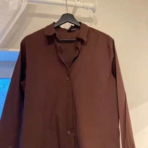 Brun skjorta - H&M  - Brun skjorta i väldigt bra skick, köpt från H&M. Den har endast ett litet hål som syns på bilden. Bortsett från det har den använts ett fåtal gånger och är i bra skick. Materialet är skönt och passar perfekt för sommaren, vilket gör den både fin för vardagliga tillfällen och vid finare event🤍