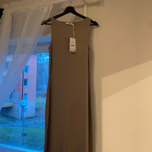 Lång klänning - NA-KD - Väldigt fin klänning i nyskick med prislappen kvar. Köpt från Nakd och har inte använts. Materialet är skönt och passar perfekt för sommaren💓