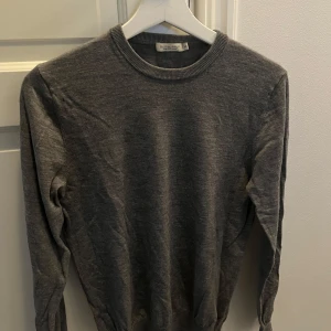 Grå merinoulltröja från Suitsupply - Säljer en stilren grå tröja i mjuk merinoull från Suitsupply. Tröjan är förvånansvärt liten i storlek. Därför anser jag att det är Stl S även om det står M.