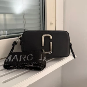 Svart axelväska Marc Jacobs - Snygg svart axelväska från Marc Jacobs. Väskan har en justerbar axelrem använd max 5 gånger och är i övrigt i jätte fint skick ( den mindre modellen, man får plats med mobil, nycklar och allt vardagligt, kan fraktas med Instabox eller mötas upp i Sundbyberg❤️