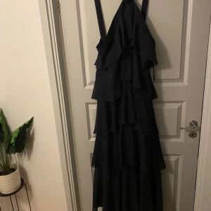 Mörkblå långklänning från Vero Moda - Elegant långklänning från Vero Moda med volangdetaljer! Denna fantastiska klänning hade jag på mig en gång på balen så praktiskt taget nyskick! Också en magisk klänning som verkligen går att använda till massa olika tillfällen. 