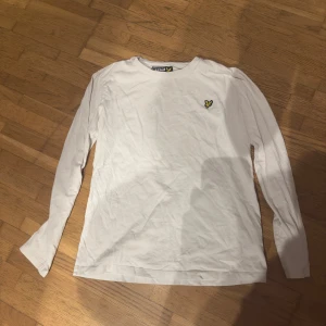 Vit långärmad tröja från Lyle & Scott - Säljer en stilren vit långärmad tröja från Lyle & Scott med deras ikoniska logga på bröstet. Perfekt för en avslappnad look.