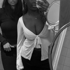 Vit långärmad topp från Design by Si - Säljer en stilren vit långärmad topp från Design by Si. Toppen har en knytning framtill som ger en snygg detalj och en v-ringad design. Perfekt för en chic och avslappnad look.