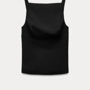 Svart korsettopp med rosetter - Elegant svart topp med dekorativa rosetter i ryggen och en diskret dragkedja i sidan. Perfekt för en stilren look. Helt oanvänd med lappar på från zara!