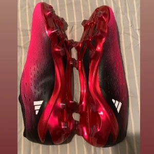  Sprillans nya Adidas X Speedportal - Ta spelet till nästa nivå med dessa helt nya fotbollsskor från Adidas! Den trendiga rosa designen med eleganta vita detaljer och en iögonfallande röd sula gör dig till stjärnan på planen. Skorna är sprillans nya och erbjuder en innovativ snörlös konstruktion för en perfekt passform och ultimat kontroll. Perfekta för dig som vill kombinera stil och prestanda. Vänta inte – säkra ditt par idag och gör varje match till din!