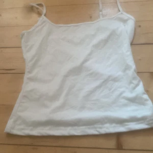 Vit linnetopp - Säljer en enkel och stilren vit linnetopp med tunna axelband. Perfekt för varma sommardagar eller som ett basplagg i garderoben.