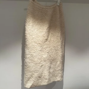 Beige stickad kjol - Mysig beige stickad kjol med en fluffig textur. Kjolen har en rak passform och är perfekt för kyligare dagar. Den neutrala färgen gör den lätt att matcha med olika toppar och accessoarer. Använd 1 gång 