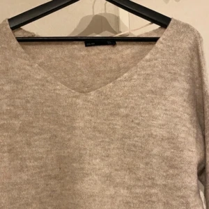 Beige stickad tröja - lager157 - En jättefin stickad tröja från Lager 157, i nyskick då den endast har använts en gång. Den är V-ringad med ett väldigt mjukt material som inte sticks. Den passar utmärkt för höst- och vintersäsongen. Tröjan är normal i storleken, vid frågor är det bara och svara🤍