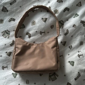 Beige axelväska från Gina Tricot - Snygg beige axelväska från Gina Tricot med dragkedja upptill + ett litet innerfack med dragkedja. Enkel och stilren design som passar till många olika outfits😊Den är i nytt skick då jag bara använt den 3-4 gånger🥰