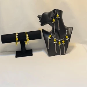 Gult och silverfärgat smyckeset - Unikt smyckeset med halsband, armband och örhängen i gult och silver. Halsbandet har stora gula pärlor och långa silverkedjor. Armbandet matchar med gula och vita pärlor. Örhängena har liknande design med hängande kedjor.Ett par örhängen och ett par armband plus en halsband handgjorda mycket mycket fint nytt oanvänd gul