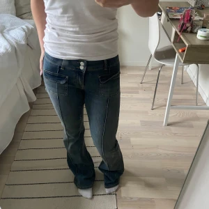 Mörkblå bootcut jeans - Snygga mörkblå bootcut jeans med låg midja och snygga fickor fram.  Köpta i höstas och endast använda ett fåtal gånger då de är för långa för mig som är 160 cm och därför är de i väldigt bra skick.  Passar superbra till både sneakers och klackar.