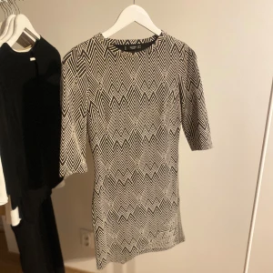 Mönstrad klänning från Mango - Snygg klänning från Mango med ett geometriskt mönster i svart och vitt. Klänningen har trekvartsärmar och en normal passform, perfekt för en stilren look.