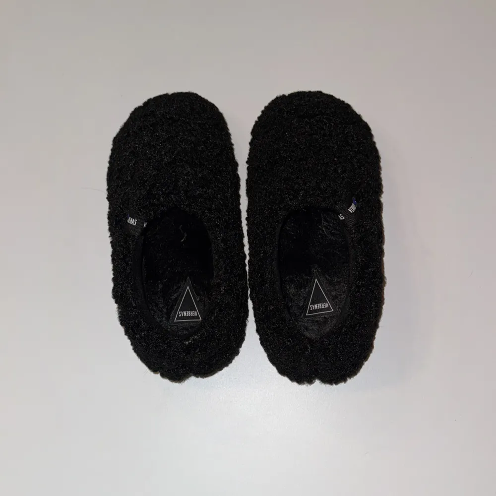 Mysiga svarta tofflor från Verbenas med en fluffig yta. Perfekta för att hålla fötterna varma och bekväma inomhus. De har en enkel design utan snörning eller andra detaljer. Helt oanvända. Kengät.