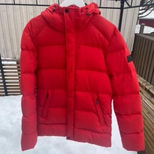 Röd dunjacka från J.Lindeberg - Säljer en snygg röd dunjacka från J.Lindeberg. Den har en stilren design med en logotyp på ärmen. Perfekt för vintern! Jacka är använd men fint skick, har en liten repa på vänster axel (se sista bild) men inget som stör eller syns tydligt. Strl M men skulle säga att den är åt M/S hållet där någonstans. Skriv vid frågor, kan gå ner något i pris vid snabb affär!