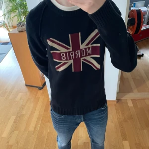 Morris Finstickad Tröja - Säljer en sjukt fet unik svart stickad tröja från Morris. Tröjan har Storbritanniens flagg på sig och är gjord i ett tjockt material. Den är i mycket bra skick och passar strl M. Hör gärna av er vid frågor eller funderingar!!